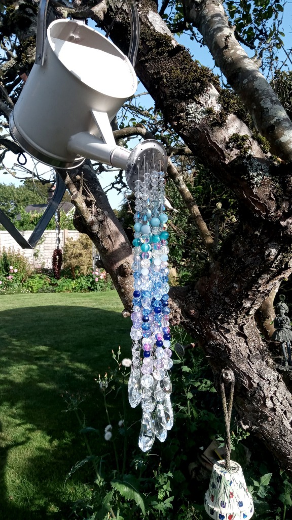 Suncatcher made using a watering can and beads threaded through the rose.